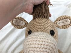 a crocheted giraffe stuffed animal being held by someone's hand