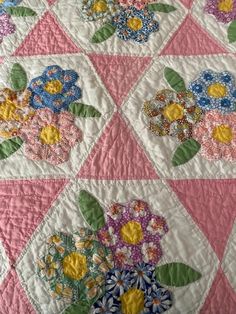 a pink and white quilt with flowers on it's side, in the center