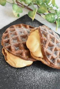 two waffles with icing on a black plate