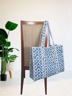 a blue and white bag sitting on top of a chair next to a potted plant