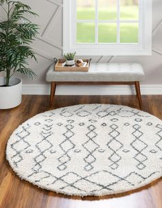 a white and black rug in front of a window with potted plants on it