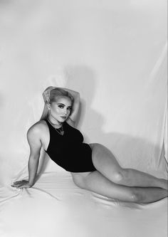 a black and white photo of a woman in a bathing suit laying on a bed