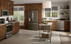 a kitchen with stainless steel appliances and wooden cabinets, including a table with two baskets on it