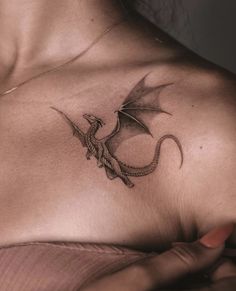 a woman's chest with a dragon tattoo on her left shoulder and right arm