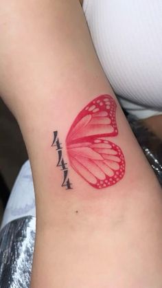 a red butterfly tattoo on the back of a woman's arm