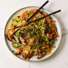 a white plate topped with meat and veggies covered in seasoning next to chopsticks