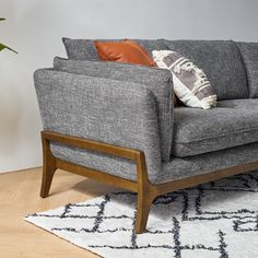 a grey couch sitting on top of a wooden floor next to a potted plant