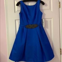 a blue dress hanging on a door with a black belt around it's waist