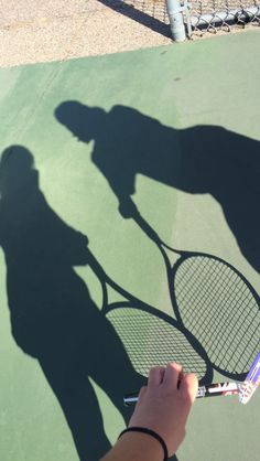 the shadow of two people holding tennis rackets