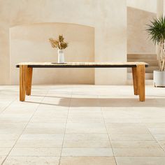 a wooden table sitting on top of a tiled floor next to a potted plant