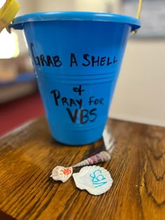 a blue bucket sitting on top of a wooden table next to a small candy bar