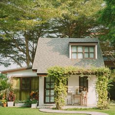 a small white house sitting in the middle of a lush green yard