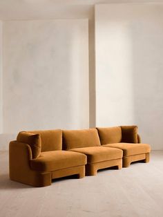 an orange couch sitting on top of a hard wood floor next to a white wall