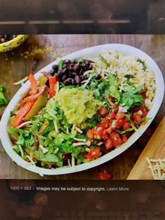 a salad with black beans, lettuce, tomatoes and avocado in a white bowl