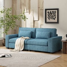 a blue couch sitting on top of a wooden floor next to a rug and table