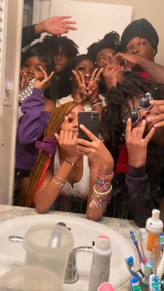 a group of people standing in front of a bathroom mirror taking pictures with their cell phones