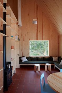 a living room with wooden walls and red tile flooring, built in shelving units