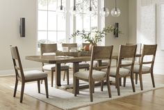 a dining room table and chairs in front of a window with an area rug on the floor