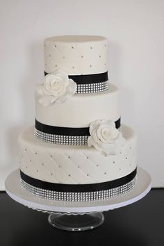 a three tiered wedding cake with white flowers and black trimmings on top