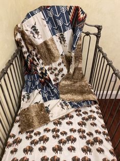 a baby crib with a blanket on top of it and an elephant print bed spread