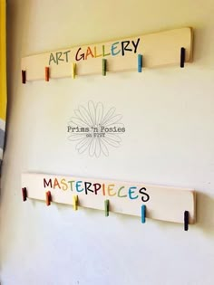 three wooden pegs are hanging on the wall in front of a sign that says art gallery