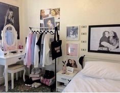 a bedroom with white walls and pictures on the wall, clothes hanging up to dry