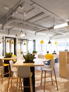 an office with yellow and white chairs, desks, and plants in the center