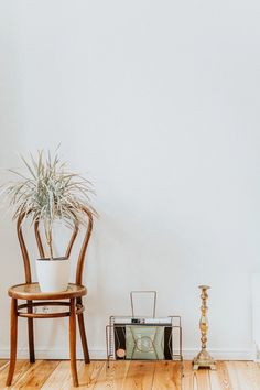 a room with a chair, plant and radio on the floor in front of a white wall