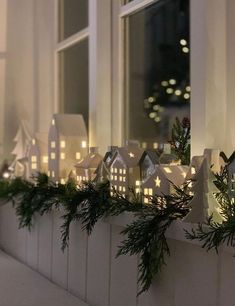 a window sill decorated with christmas lights and greenery in front of a house