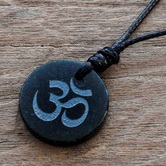 Carved from dark green jade â so dark it appears almost black â the Om symbol of Lord Shiva flourishes like ancient calligraphy. This mantra is used in mystical contemplation of ultimate reality and is considered the resonant body of the absolute. From Jorge Lopez the elegant pendant is worn on a black cotton necklace. Its length can be adjusted by sliding the knots along the cords. Please note: Etched image may fade somewhat over time as a result of absorbing body oils and/or skincare produ Black Carved Symbolic Necklace, Black Symbolic Carved Necklace, Symbolic Black Carved Necklace, Symbolic Black Necklaces For Good Luck, Symbolic Black Etched Jewelry, Black Etched Spiritual Jewelry, Black Jade Jewelry For Gifts, Traditional Black Etched Jewelry, Ancient Calligraphy