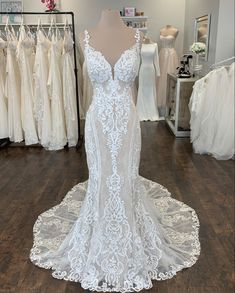 a white wedding dress on display in a bridal gown shop with mannequins