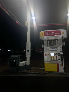 an empty gas station at night with the lights on and no people around it,