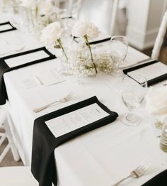 the table is set with black and white linens, silverware, and flowers