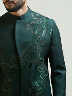 a man wearing a green jacket with an embroidered design on the front and back side