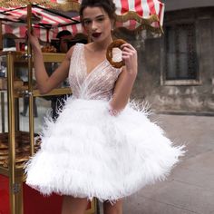 a woman in a white dress holding a donut