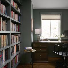 a home office with bookshelves, desk and chair in front of the window