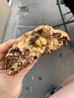 a person holding a half eaten chocolate chip cookie