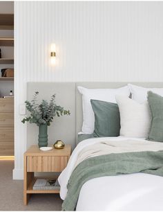 a bedroom with white walls and green pillows