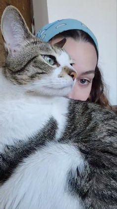 a woman is holding a cat with her face close to it's head while she looks at the camera