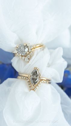 two wedding rings sitting on top of each other with flowers in the backgroun