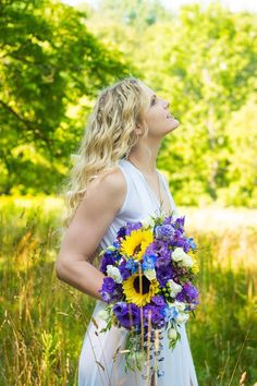 a woman in a white dress holding a purple and yellow bouquet