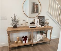 a wooden table topped with candles next to a christmas tree and other decorations on top of a hard wood floor