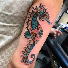 a colorful sea horse tattoo on the arm