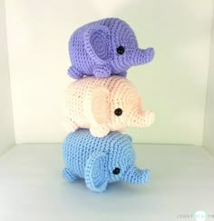 three crocheted elephants sitting on top of each other in front of a white wall