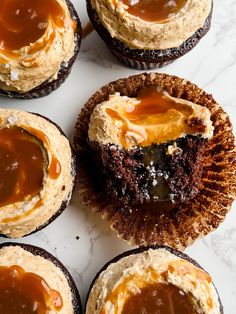 chocolate cupcakes with peanut butter frosting and caramel sauce on top, sitting on a marble surface