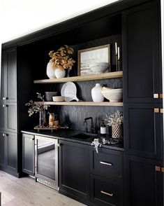 a kitchen with black cabinets and white vases