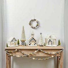 a wooden table topped with christmas decorations and a clock mounted on the wall behind it