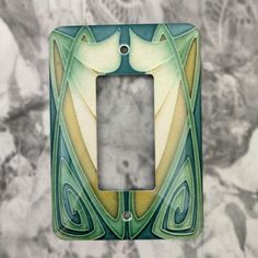 a decorative light switch plate cover in green, yellow and white with an abstract design