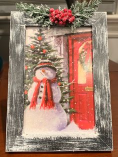 a snowman in front of a red door with a christmas wreath on it's head