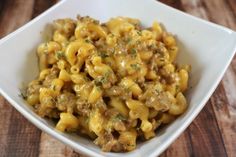 a white bowl filled with macaroni and cheese on top of a wooden table